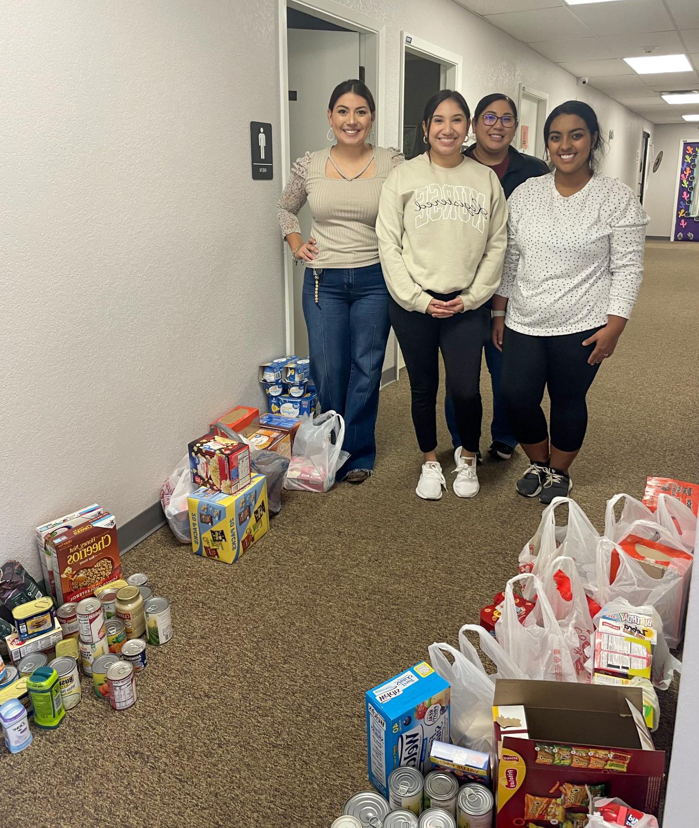 Students from the Student Nurses Association Club pose alongside bags of donations.